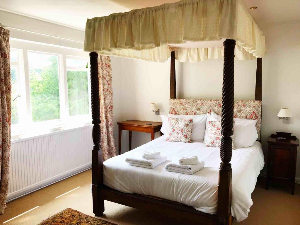 a bedroom with a canopy bed with towels on it at Owlpen Manor Cottages in Uley