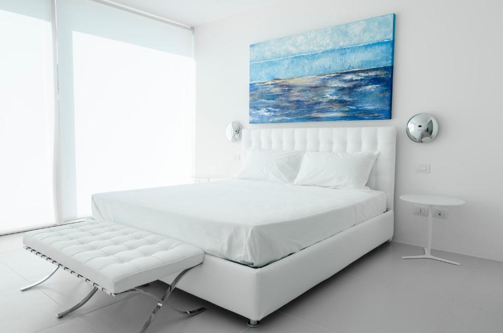 a white bedroom with a large bed and a chair at Portopalosuite in Portopalo