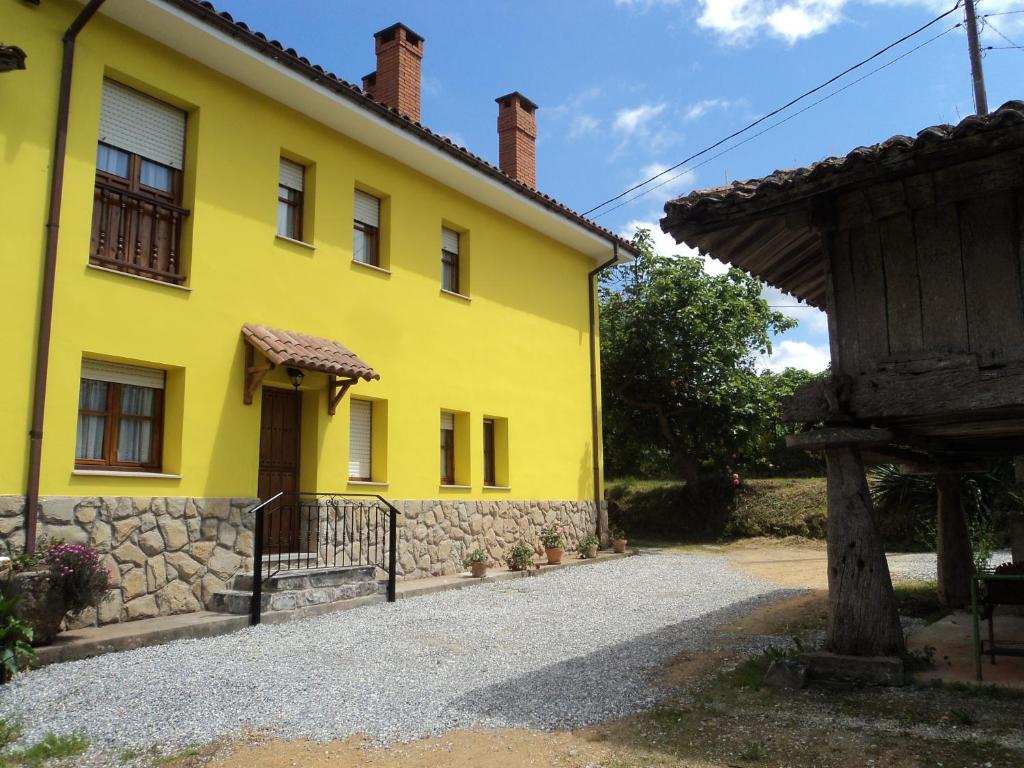 a yellow house with a gate and a building at APARTAMENTOS RURALES PERNÚS in Colunga