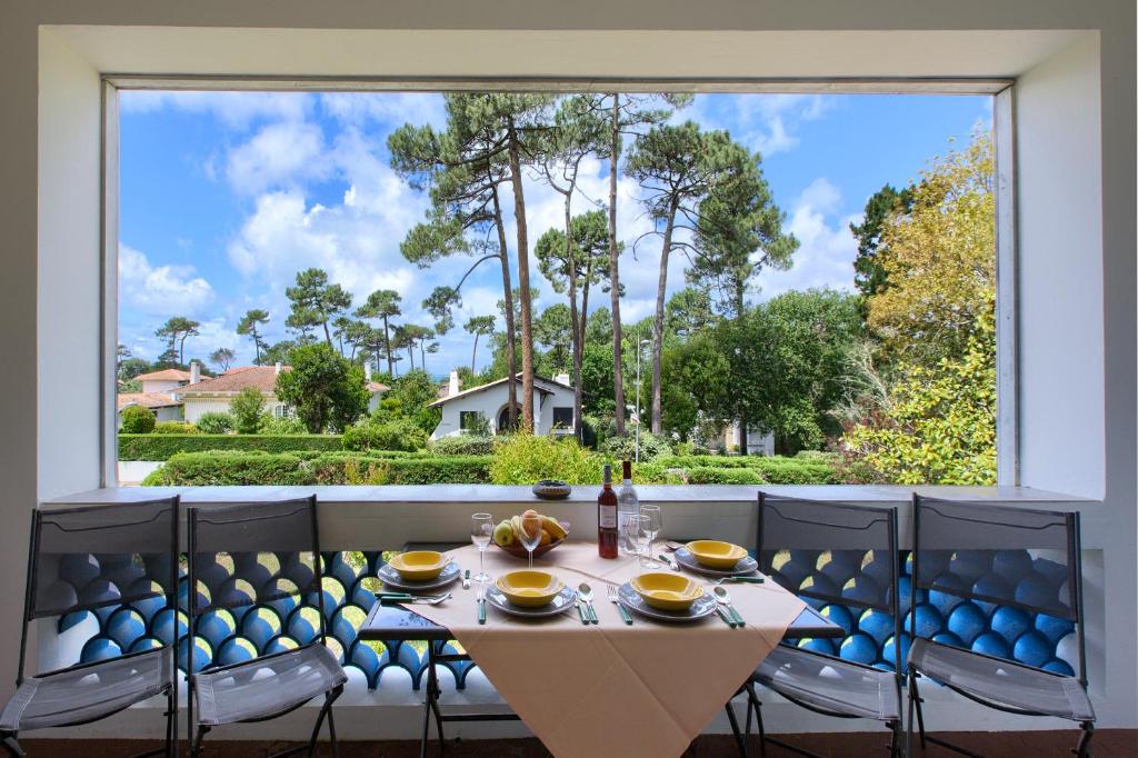 une table et des chaises dans une chambre avec une grande fenêtre dans l'établissement Appartement Pyla Les Cèdres, à Pyla-sur-Mer