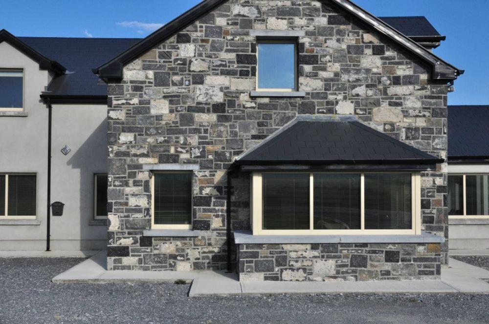 una casa in mattoni con due finestre sopra di Doolin Village Accomodation a Doolin