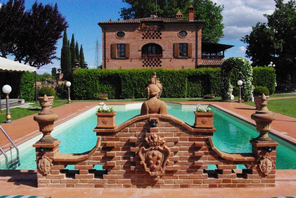 una fuente frente a una casa con un edificio en Villa Portoverde, en Foiano della Chiana
