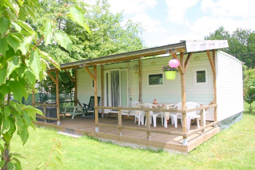 a house with a deck with a table and chairs at Mobile Home at La Petite Lande in Pierrefiche