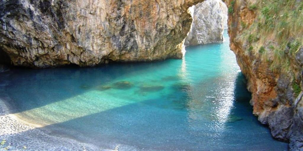 una gran piscina de agua azul junto a un acantilado en SCALEA - RIVIERA DEI CEDRI en Scalea