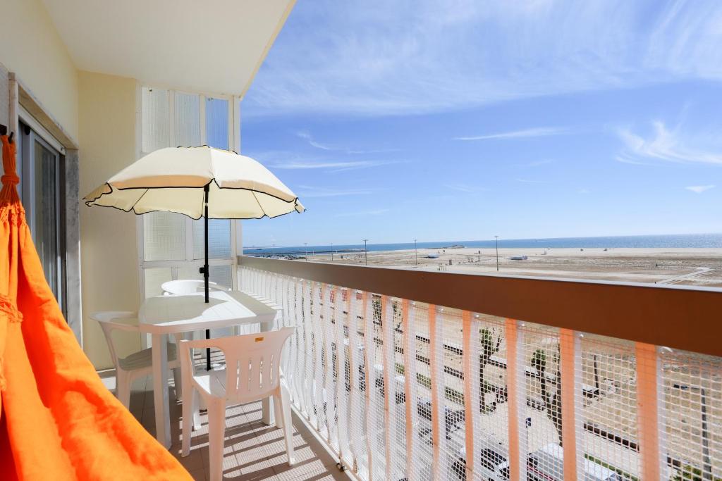 a balcony with a table and an umbrella on a beach at Apartamento Mar Azul in Figueira da Foz