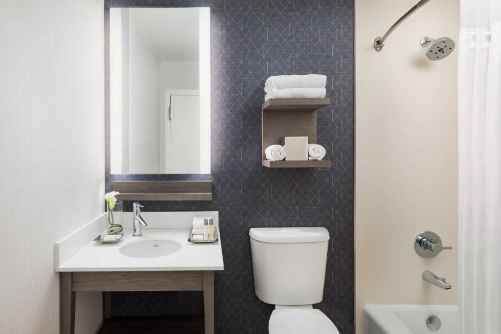 a bathroom with a toilet, sink, and mirror at Hotel Caza Fisherman's Wharf in San Francisco