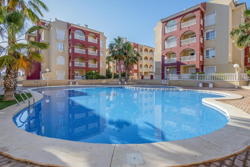 ein großer Pool vor einigen Apartmentgebäuden in der Unterkunft Isla del Baron - A Murcia Holiday Rentals Property in Los Alcázares