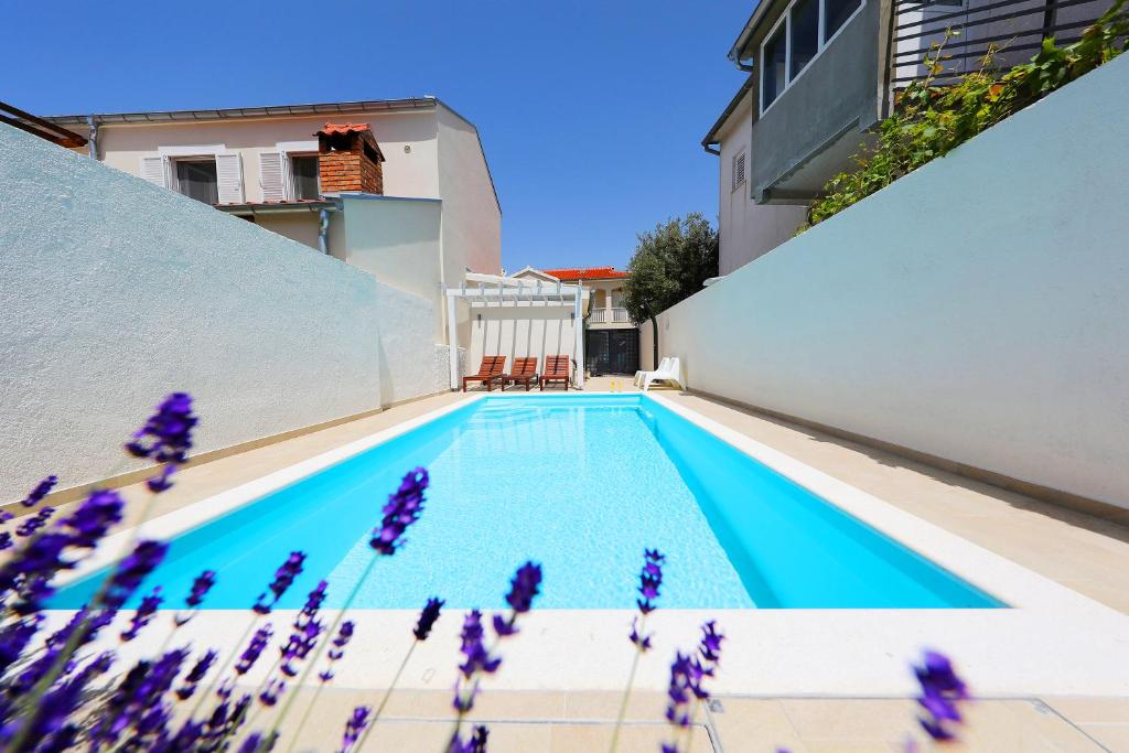 a swimming pool with purple flowers next to a building at Luxury Villa Claudia with Pool in Zadar