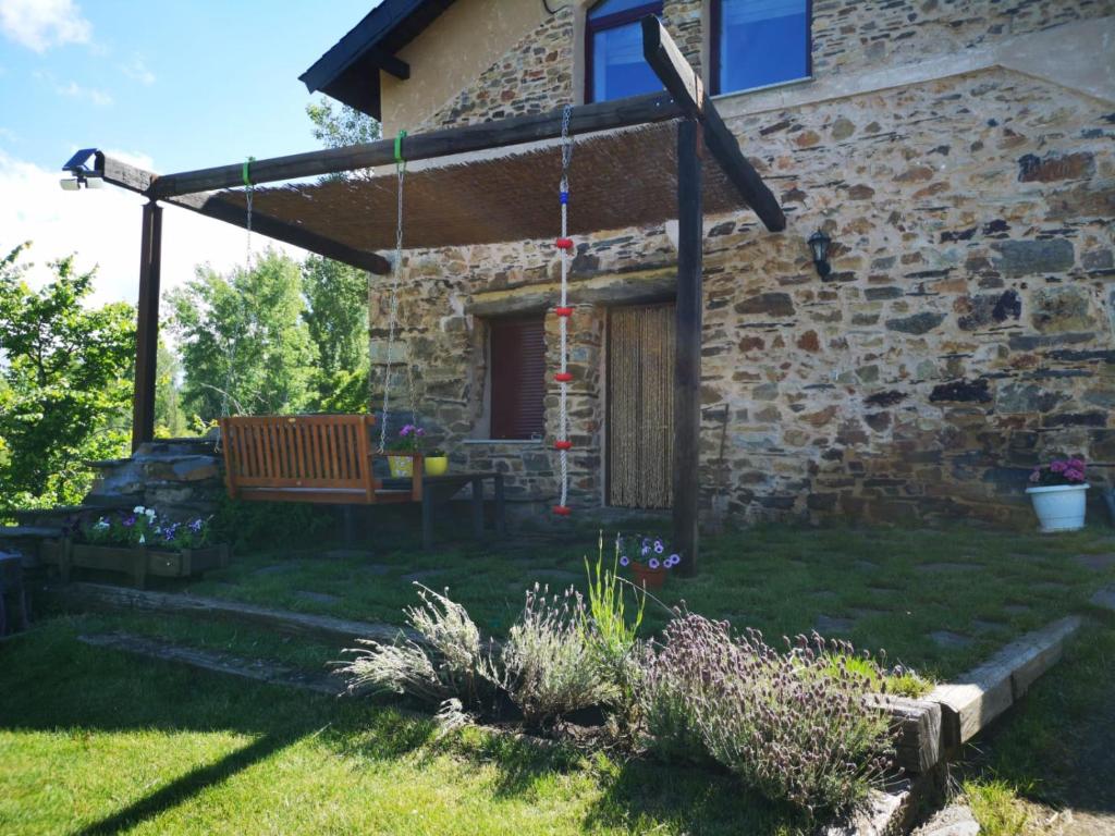 ein Steinhaus mit einer Pergola und einer Bank in der Unterkunft Casa Ucedo in Ucedo