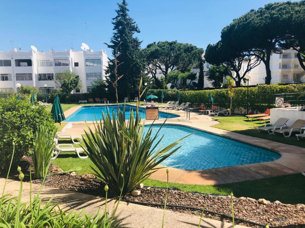 una piscina con sillas y un edificio en Casa da Garça, en Quarteira