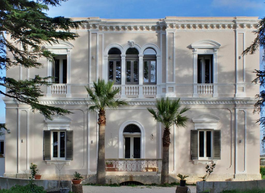 una grande casa bianca con palme di fronte di Villa Camilla a Mola di Bari