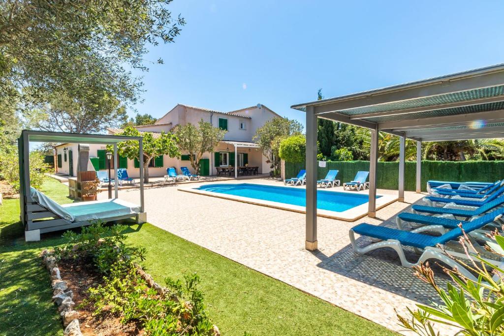 a swimming pool with blue lounge chairs in a backyard at Casa Aurora in Cala Santanyi