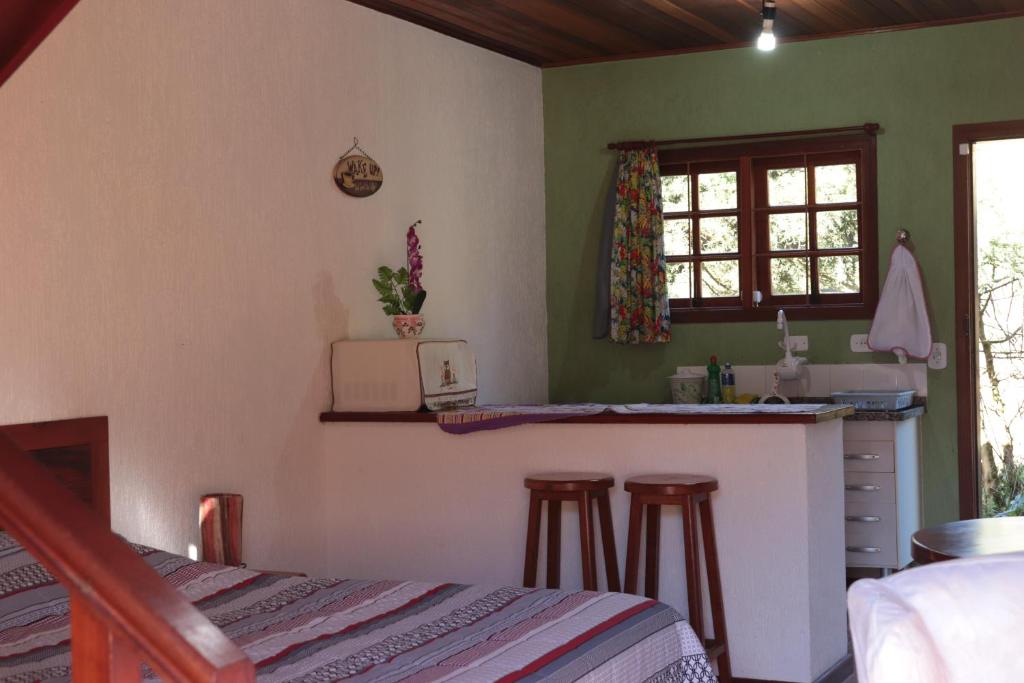 a kitchen with a counter and stools in a room at Chalé Recanto do Sossego in Gonçalves