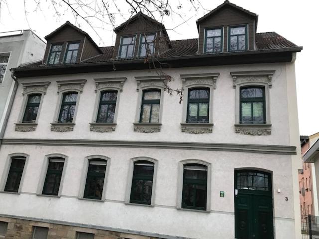 - un grand bâtiment blanc avec des fenêtres et une porte verte dans l'établissement Gästewohnung Saaleblick, à Weißenfels