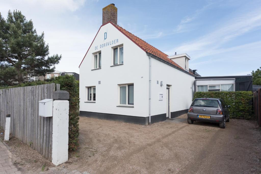 een wit huis met een auto ervoor geparkeerd bij De Dorsvloer in Domburg