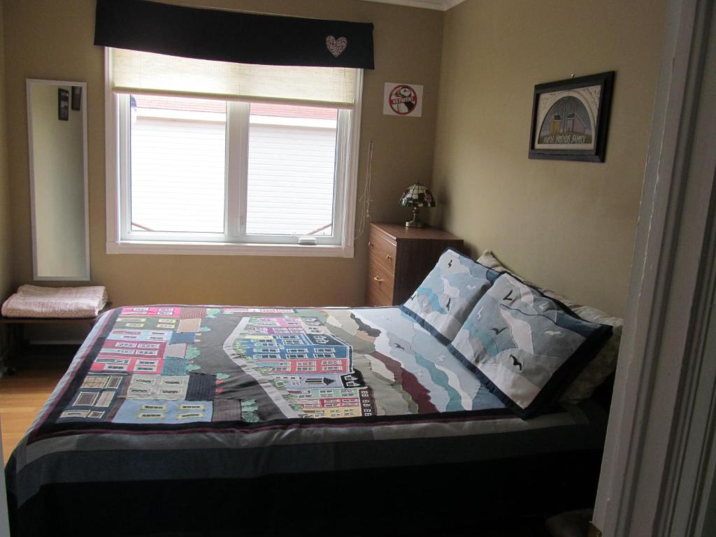 a bedroom with a bed with a quilt on it at Exploits Inn and Suites in Botwood