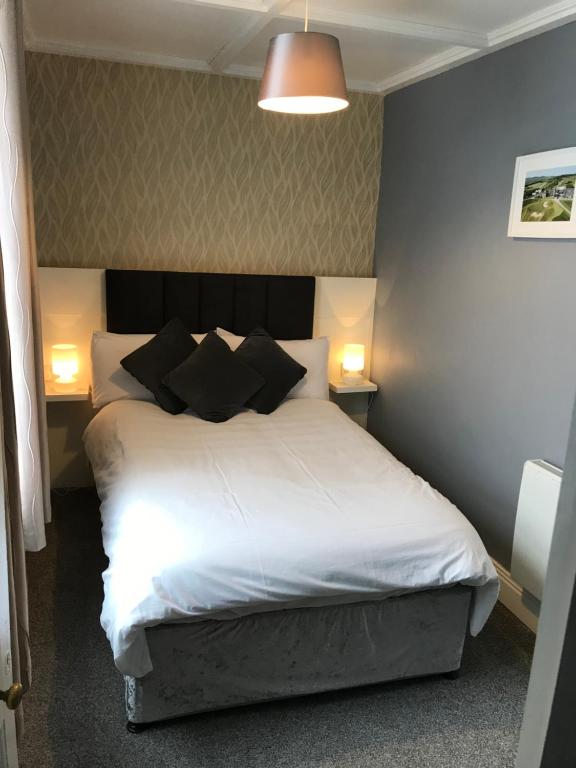 a bedroom with a white bed with black pillows at Mary Ann's Ballyheigue Cottage in Tralee