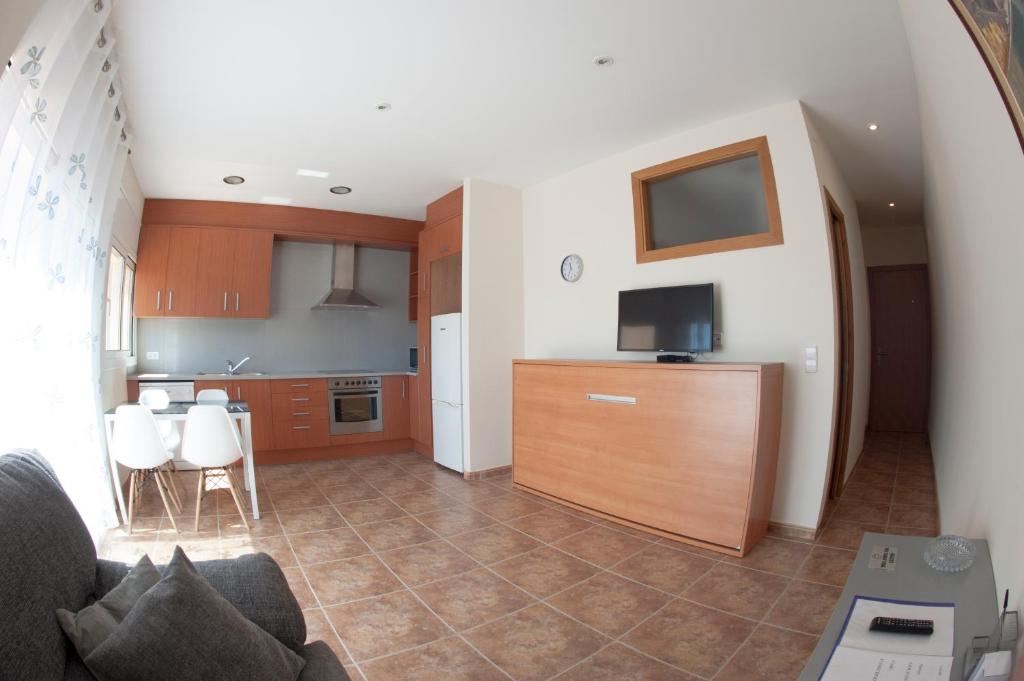 a kitchen and living room with a couch and a tv at Apartament Can Jaumató in Sant Quirze de Besora