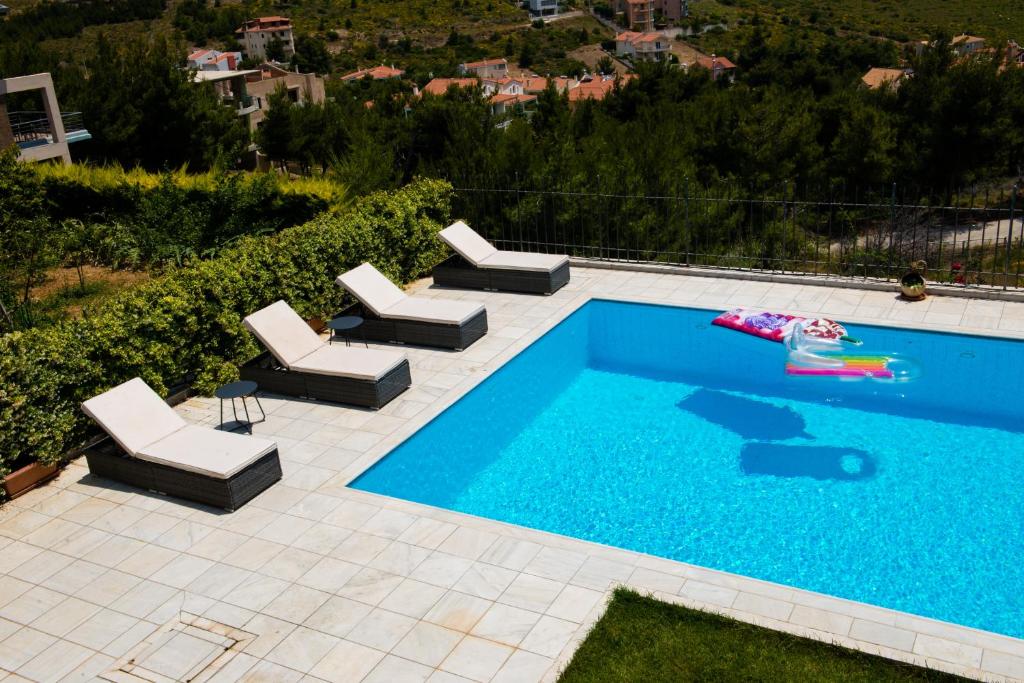 Villa Olympia VIP في Drafí: مسبح مع كراسي جلوس الكراسي ومسبح