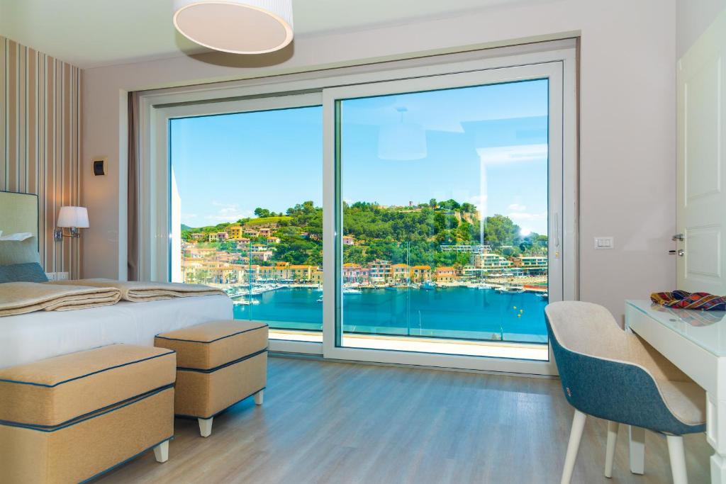 a bedroom with a large window with a view of the water at Hotel Plaza in Porto Azzurro