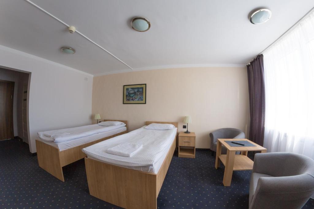 a hospital room with two beds and a chair at HOMER Bydgoszcz Ośrodek Rehabilitacji i Szkolenia PZN in Bydgoszcz
