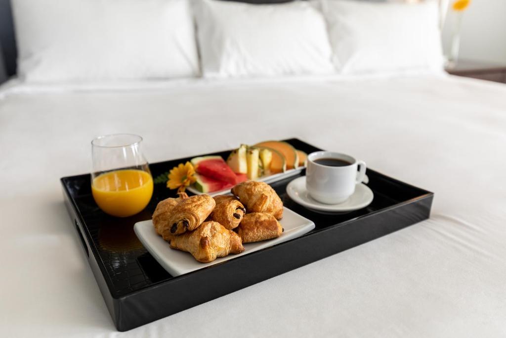 a tray with a plate of food and a cup of orange juice at Imperia Hotel & Suites Saint-Eustache in Saint-Eustache