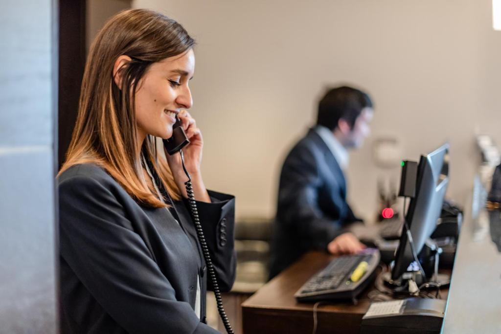 a woman talking on a phone in an office at Imperia Hotel & Suites Saint-Eustache in Saint-Eustache