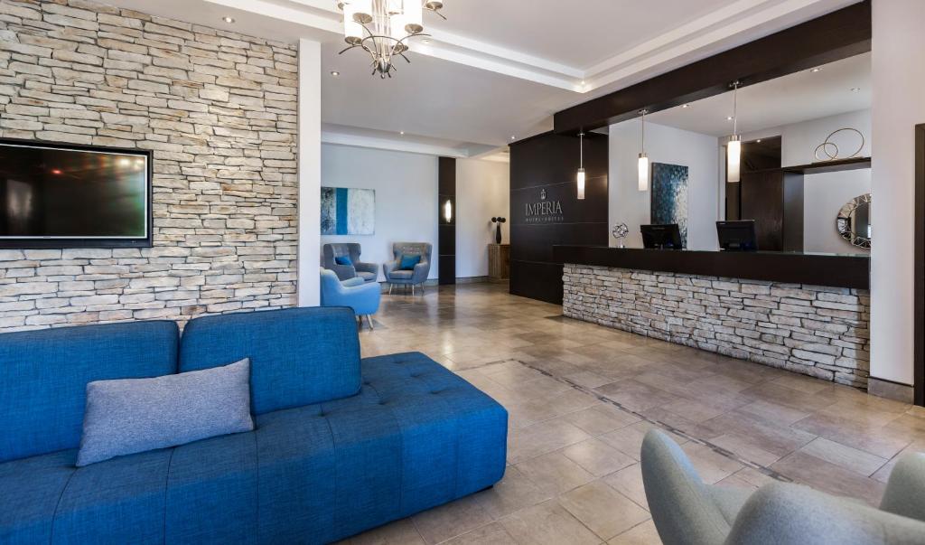 sala de estar con sofá azul y pared de ladrillo en Imperia Hotel & Suites Saint-Eustache, en Saint-Eustache