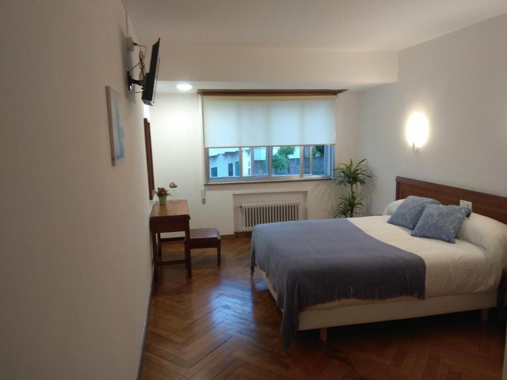 1 dormitorio con cama y ventana en La mesa del cocinero, en Lugo