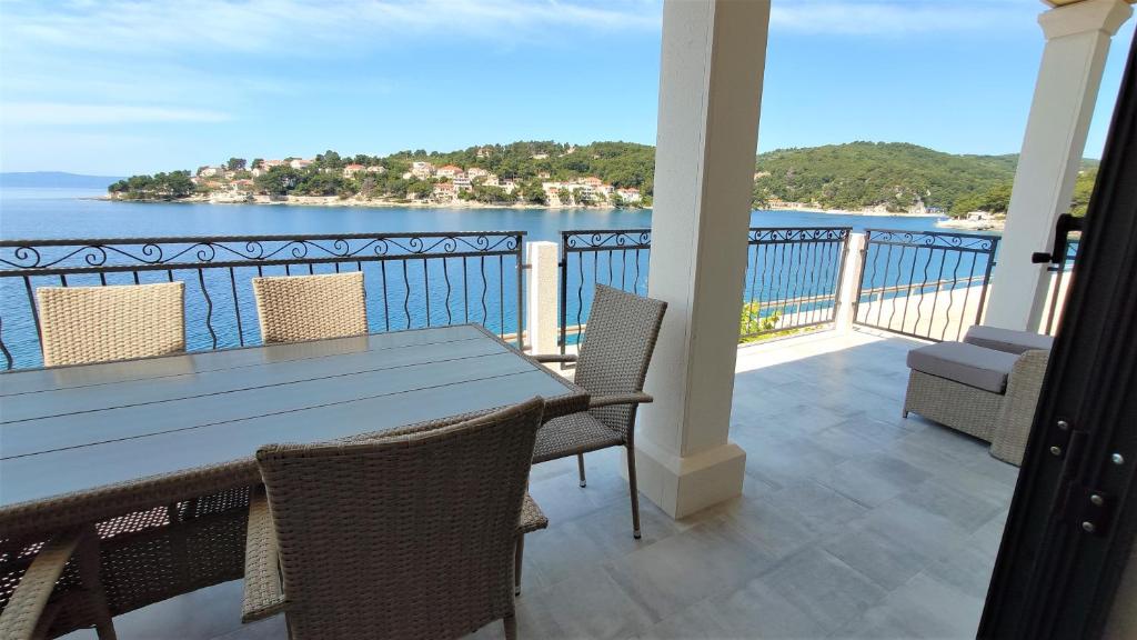 einen Tisch und Stühle auf einem Balkon mit Blick auf das Wasser in der Unterkunft ARIA in Sumartin