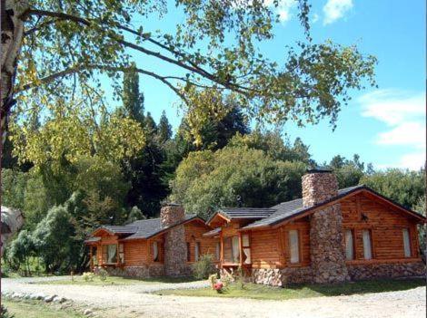 uma casa de madeira com uma árvore em Cabañas En el Corazón del Bosque em San Carlos de Bariloche
