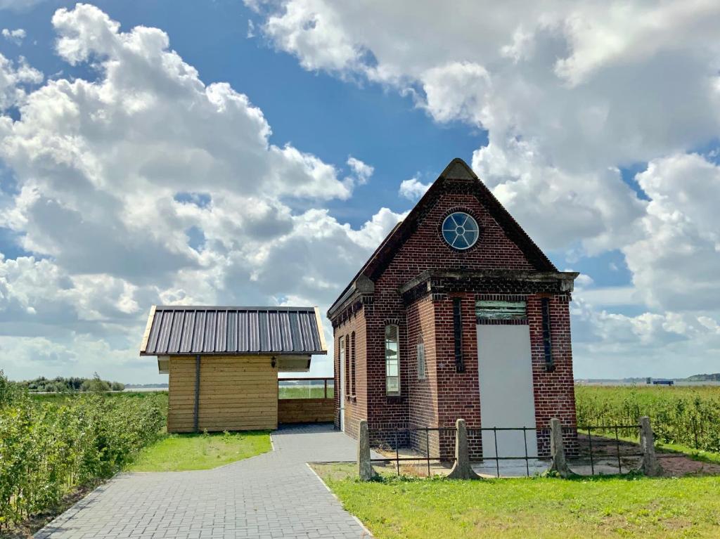 um pequeno edifício de tijolos no meio de um campo em Vakantiewoning Het Gemaal em Oostwold