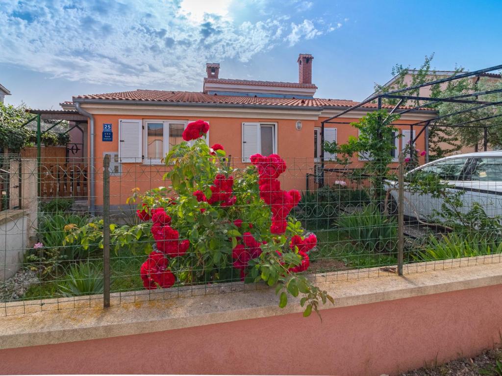 a fence with red roses in front of a house at Apartman Arijana 3 in Medulin