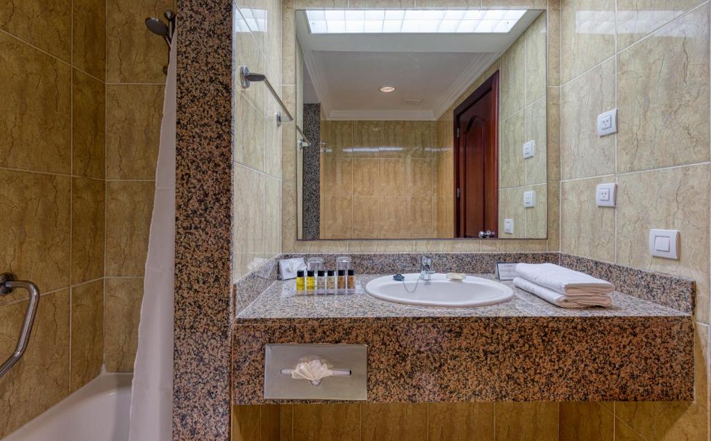 Bathroom with granite vanity, round sink, large mirror, toiletries, and tiled shower area.