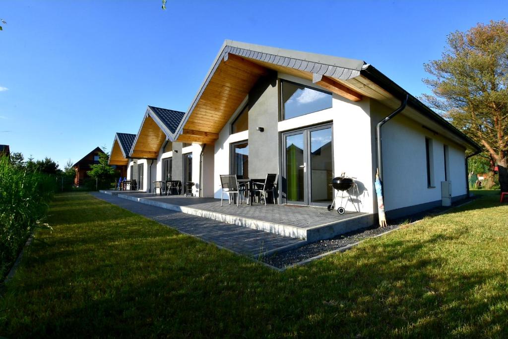 a white house with a deck with tables and chairs at Domki na Rozanej in Rowy