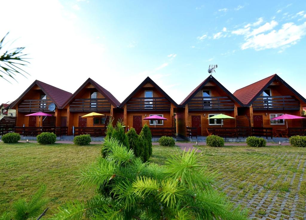 a resort with wooden buildings and a grass yard at Domki na Różanej 2 in Rowy