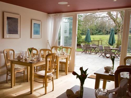 a dining room with tables and chairs and a patio at Brasteds Lodge in Norwich