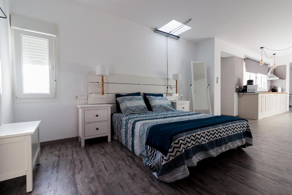 a white bedroom with a bed and a window at Apartamento Loft Sopranis in Cádiz