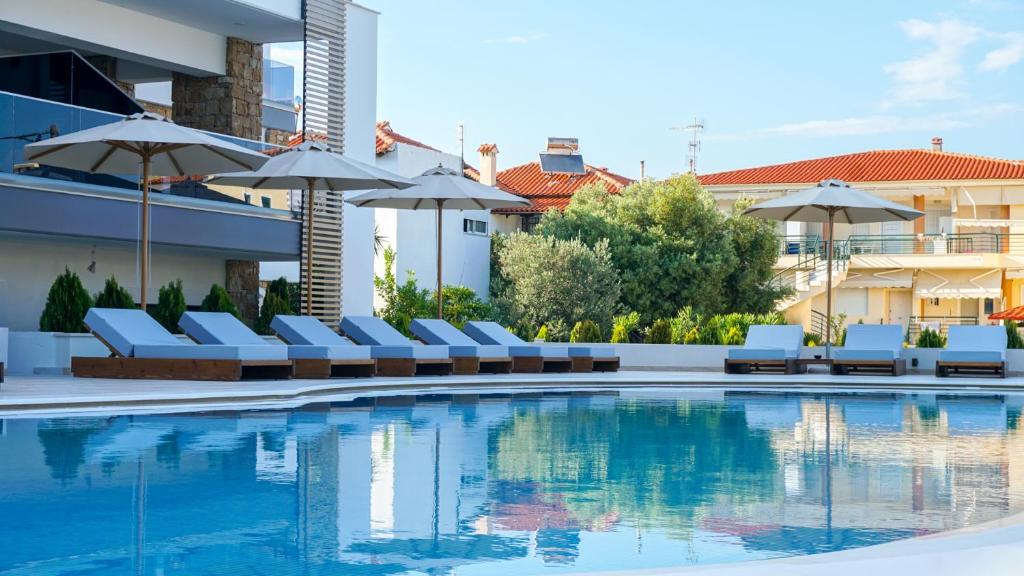 a swimming pool with lounge chairs and umbrellas at Agnes Deluxe Hotel in Pefkohori