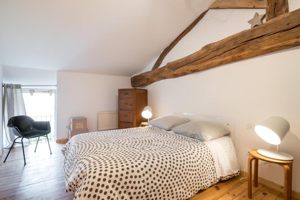 sypialnia z białym łóżkiem i czarnym krzesłem w obiekcie Gite le Pot de Vin w mieście Lancié