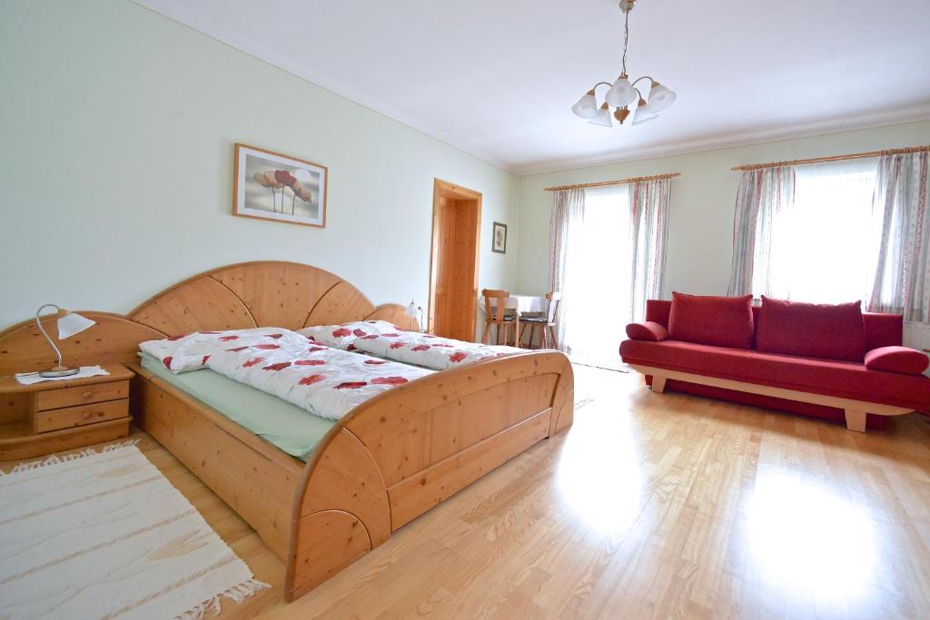 una camera con un grande letto in legno e un divano rosso di Müllnerbauer a Napplach