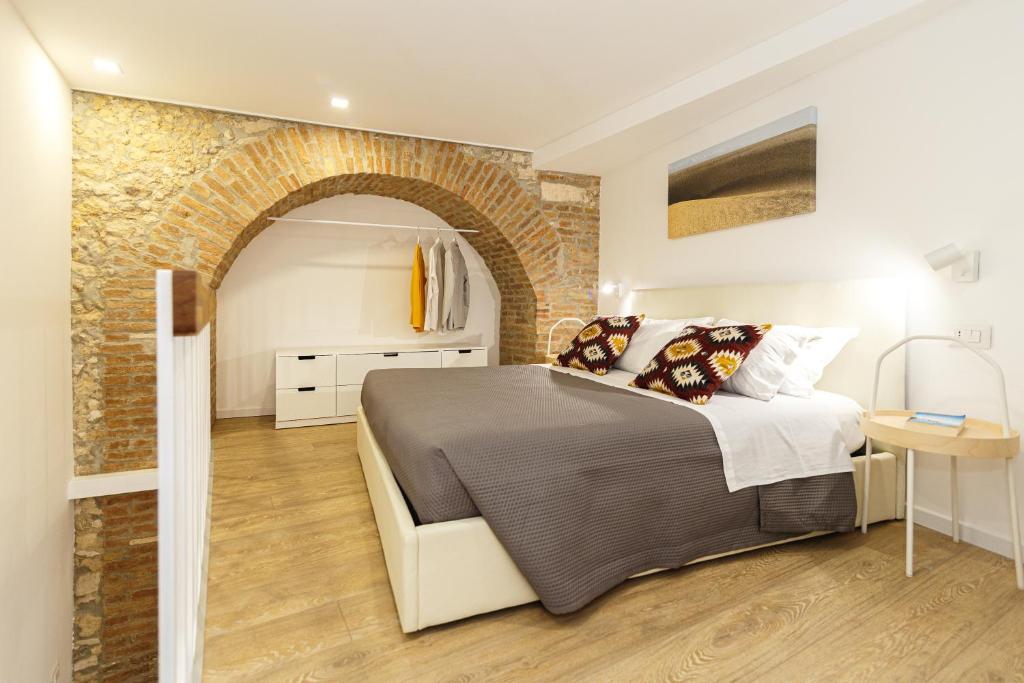 a bedroom with a bed and a brick wall at Casa Marene Ortigia in Siracusa
