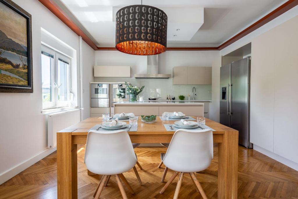 una cucina e una sala da pranzo con tavolo in legno e sedie bianche di Vila Tivoli a Lubiana