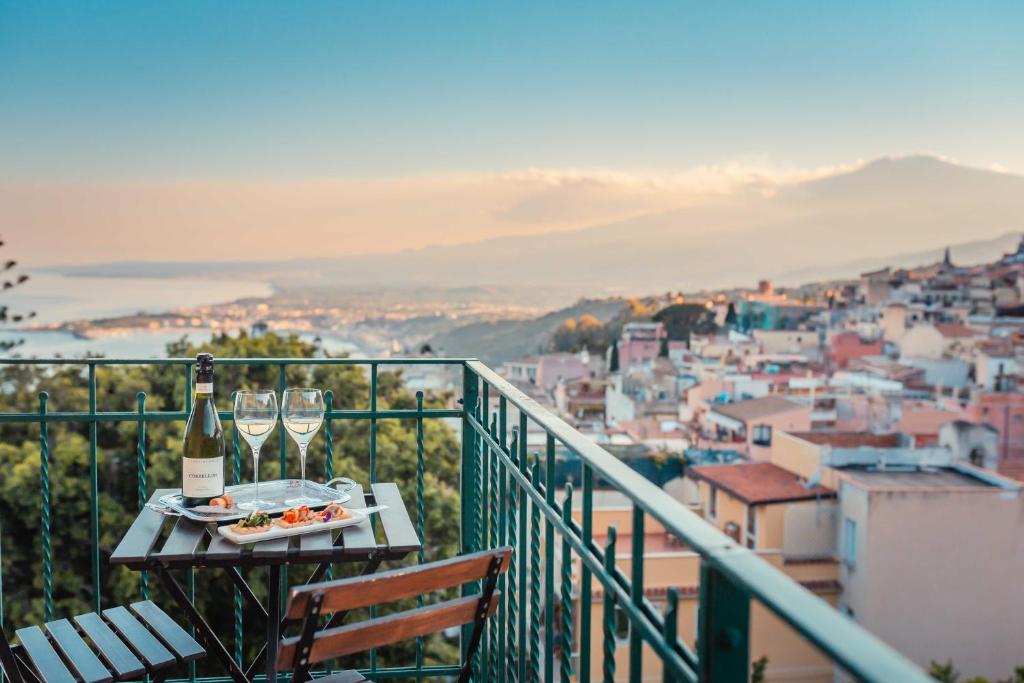 un tavolo con una bottiglia di vino e bicchieri sul balcone di B&B Teatro Greco 39 a Taormina