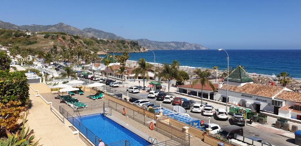 a town with a parking lot with a pool and a beach at Apartamentos Nerja Bahia in Nerja