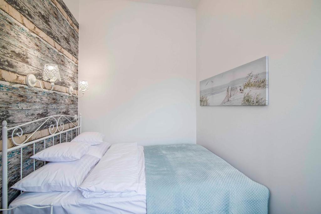 a bed in a white room with a brick wall at Apartamenty Dominikańskie in Toruń