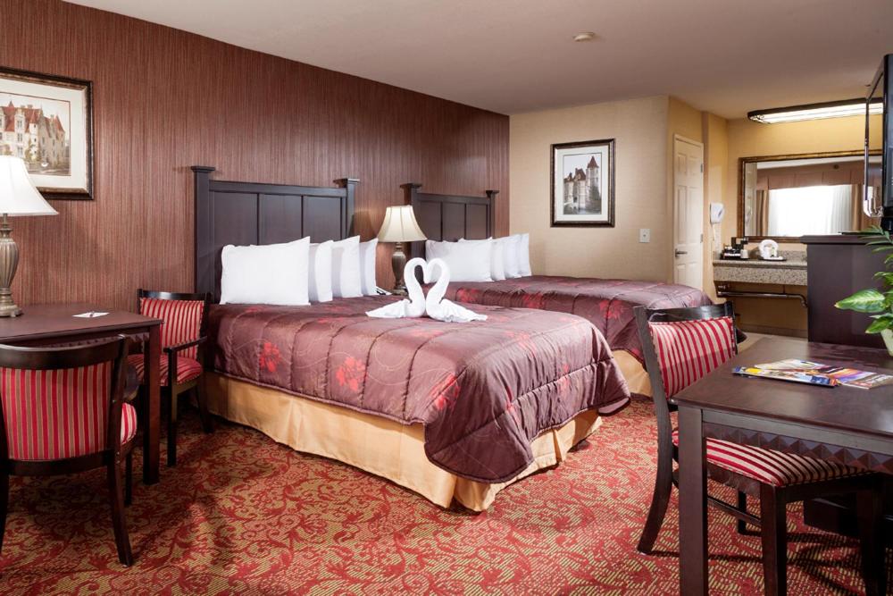 a hotel room with two beds and a table and chairs at Castle Inn and Suites Anaheim in Anaheim