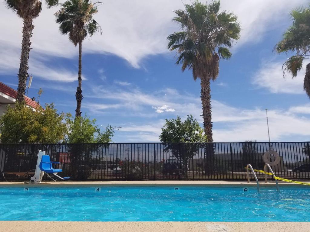 a swimming pool with palm trees and a fence at Minsk Hotels - Extended Stay, I-10 Tucson Airport in Tucson