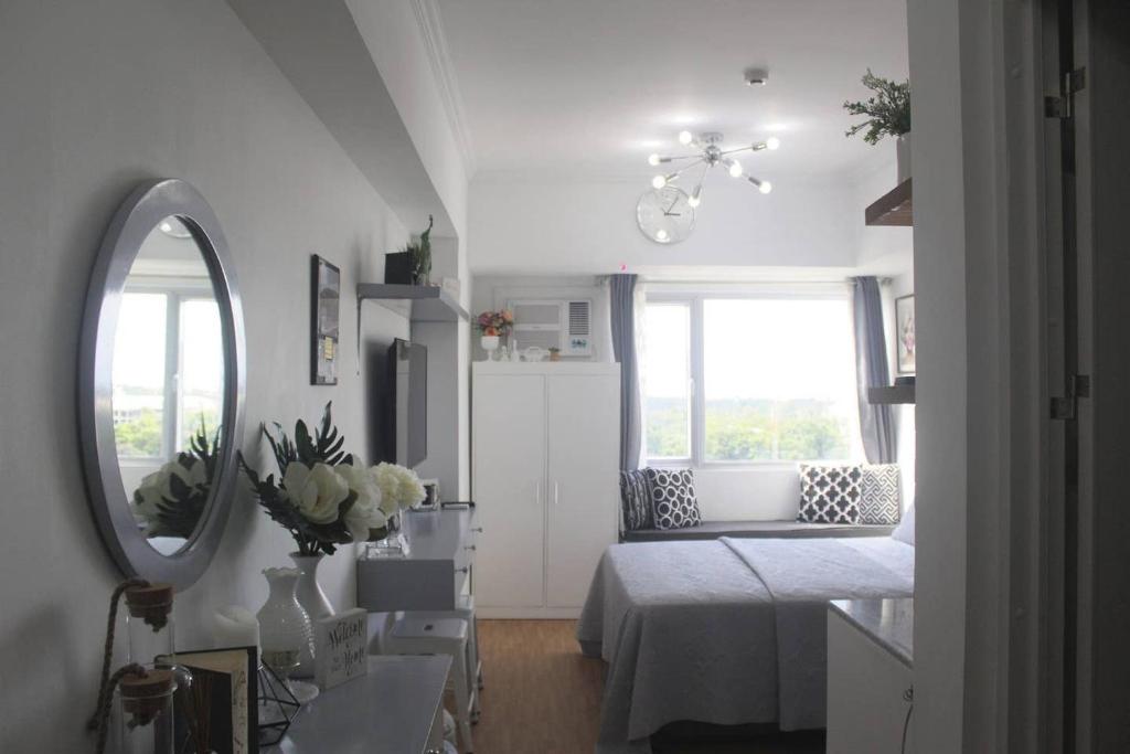Una habitación blanca con una cama y un espejo. en New York Suite 1 at Avida Towers Aspira, en Cagayan de Oro