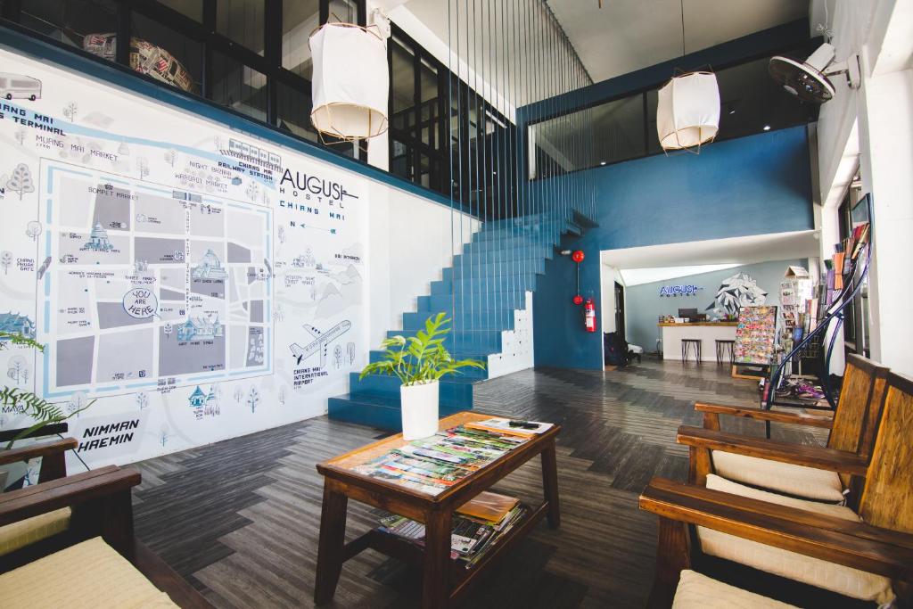 a room with a table and a large wall with drawings at The August Hostel in Chiang Mai
